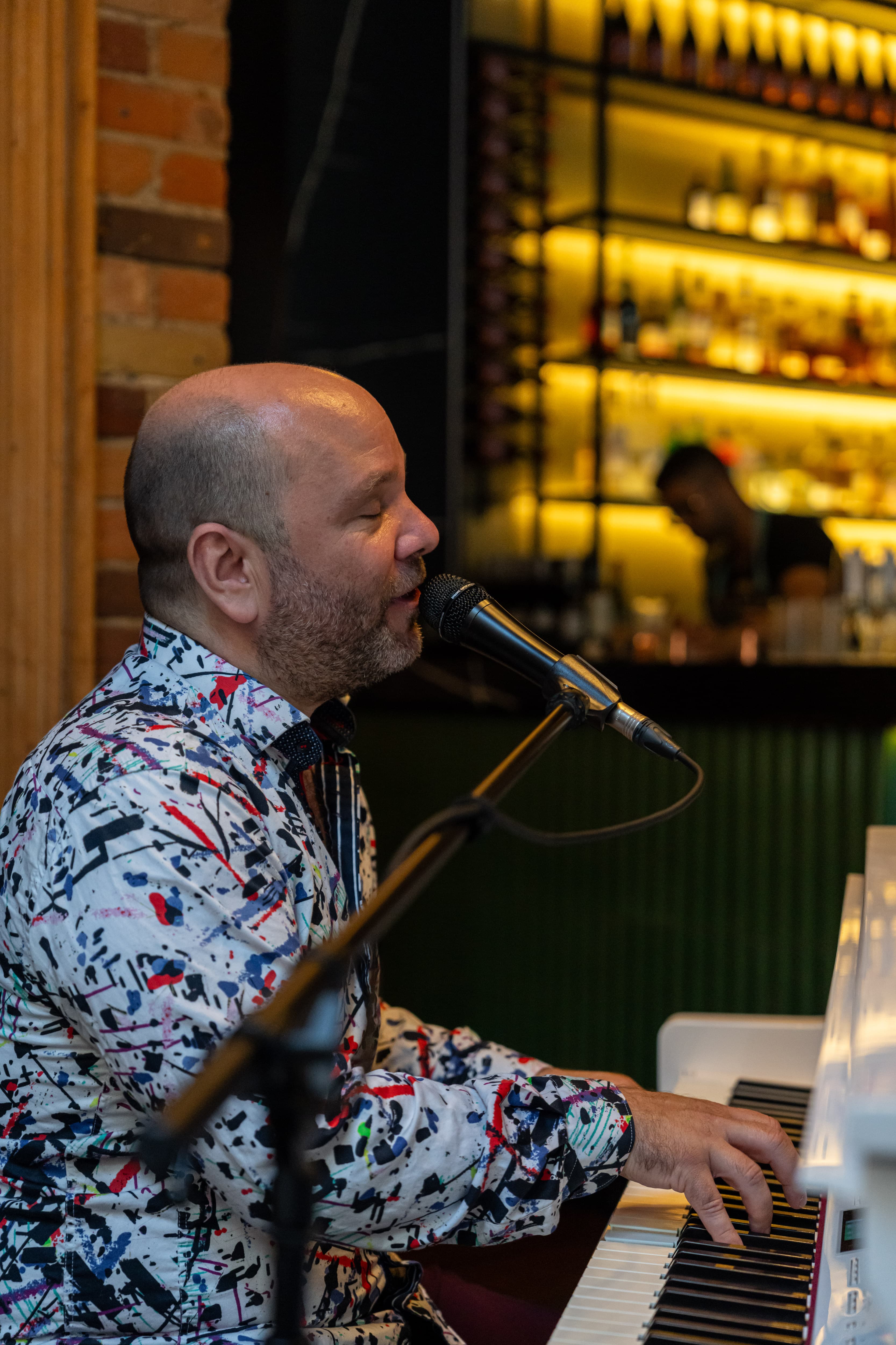 Pianist at the white grand piano with the amber-lit bar behind at The Berczy Tavern in Toronto
